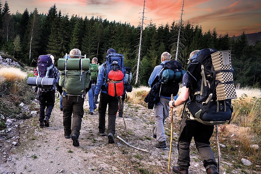Sex kursdeltagare på vandring med packade ryggsäckar på ryggen.